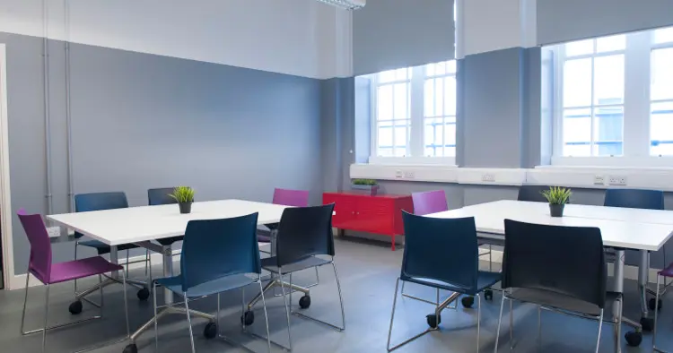 Cabaret set up for 12 people - white table, grey walls, purple and navy chairs