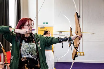Girl holding bow draws back an arrow