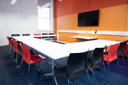 Bright meeting room set up horseshoe style with 12 chairs.