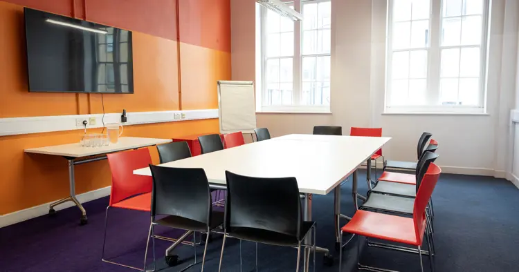 Bright meeting room set up board room style with 12 chairs. 