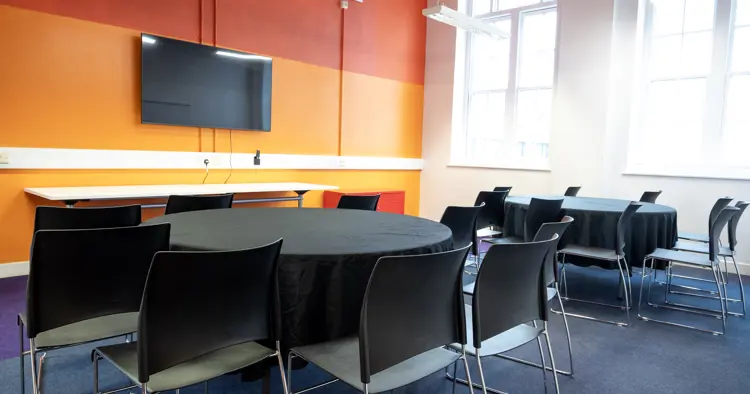 Meeting room with  two table set up with 8 chairs each. 